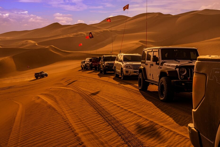 4WD convoy navigating vibrant red sand dunes during a guided Simpson Desert tour in the Australian outback.