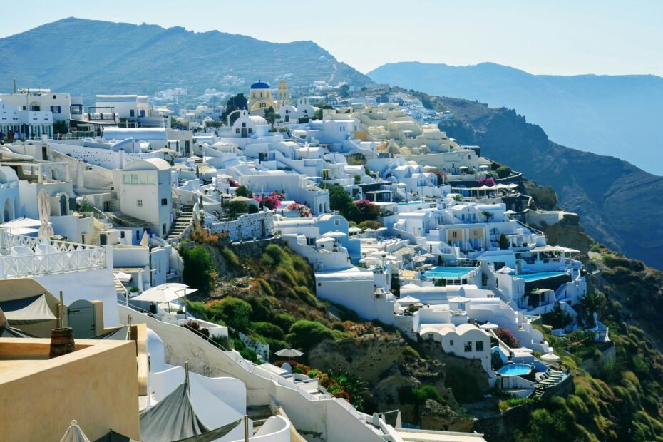 Breathtaking view of iconic whitewashed Greek island village with blue domed churches overlooking the crystal-clear Aegean Sea, representing the best places in Greece to travel.