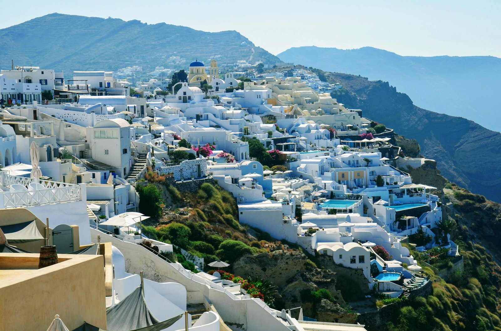 Breathtaking view of iconic whitewashed Greek island village with blue domed churches overlooking the crystal-clear Aegean Sea, representing the best places in Greece to travel.
