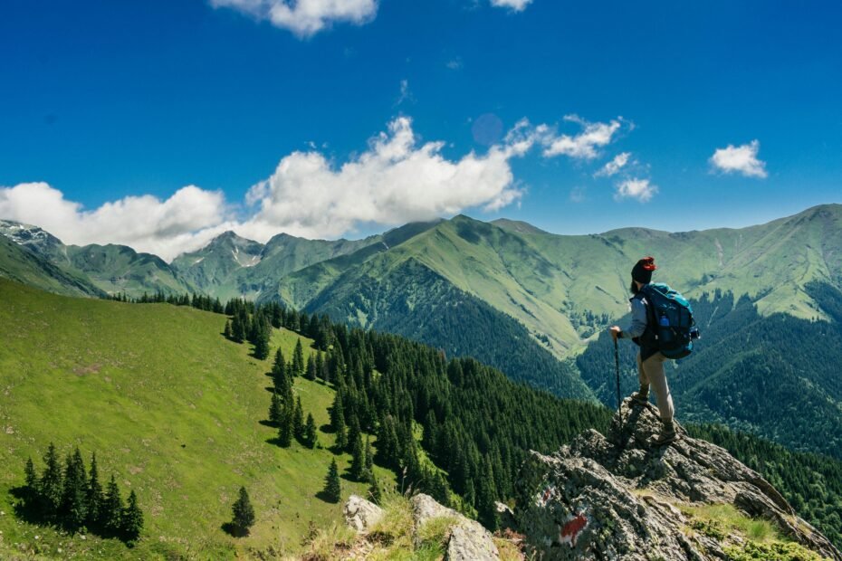 A traveler with a backpack looks out over a stunning mountain valley, illustrating the adventure found in the cheapest places to visit on a budget.