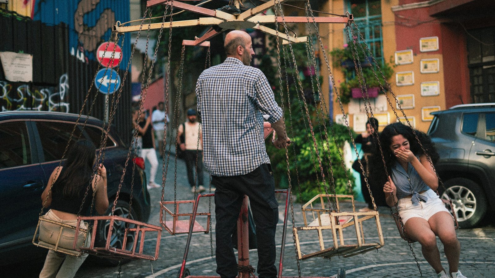 A young traveler with a backpack smiles while looking at a map on a picturesque cobblestone street, an example of an engaging budget travel activity.