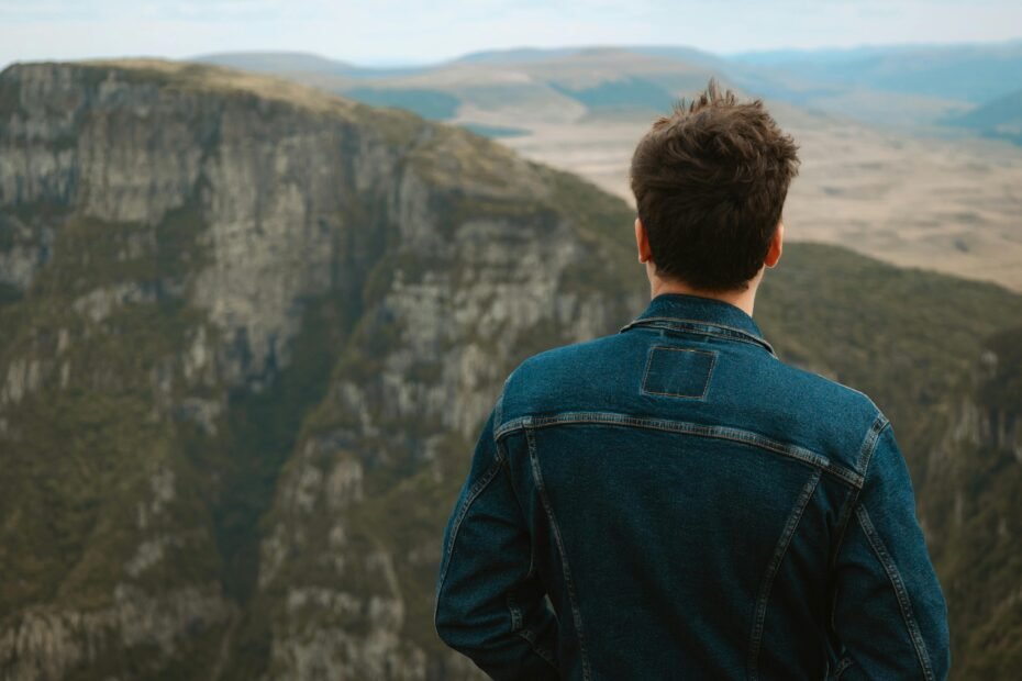 A traveler with a backpack looks out over a vast, beautiful landscape, illustrating one of the many cheap locations to travel for an affordable adventure.