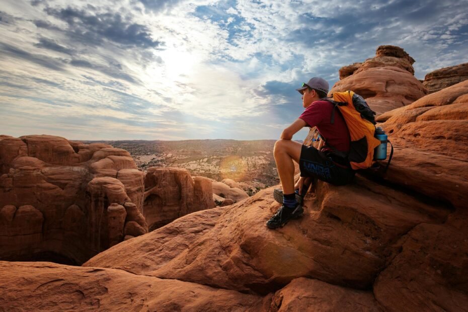 A prepared traveler with a backpack hiking across a vast desert landscape at sunrise, illustrating key preparations for a safe and memorable desert traveling adventure in 2025.