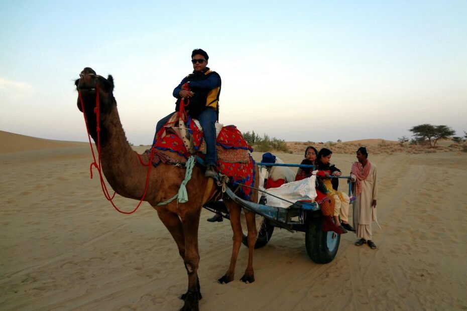 A camel caravan trekking across vast sand dunes during a golden sunset, illustrating an unforgettable Sahara desert vacation adventure.
