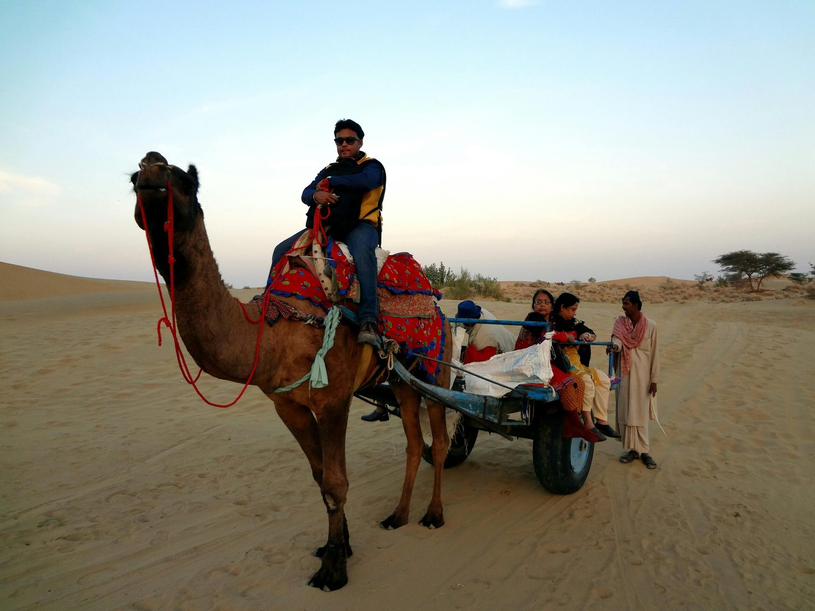 A camel caravan trekking across vast sand dunes during a golden sunset, illustrating an unforgettable Sahara desert vacation adventure.