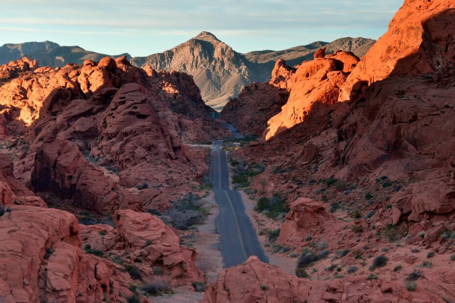 Vibrant sunset over the vast Mojave Desert landscape near Las Vegas, with the sun's golden light illuminating the iconic red sandstone formations of Valley of Fire State Park.