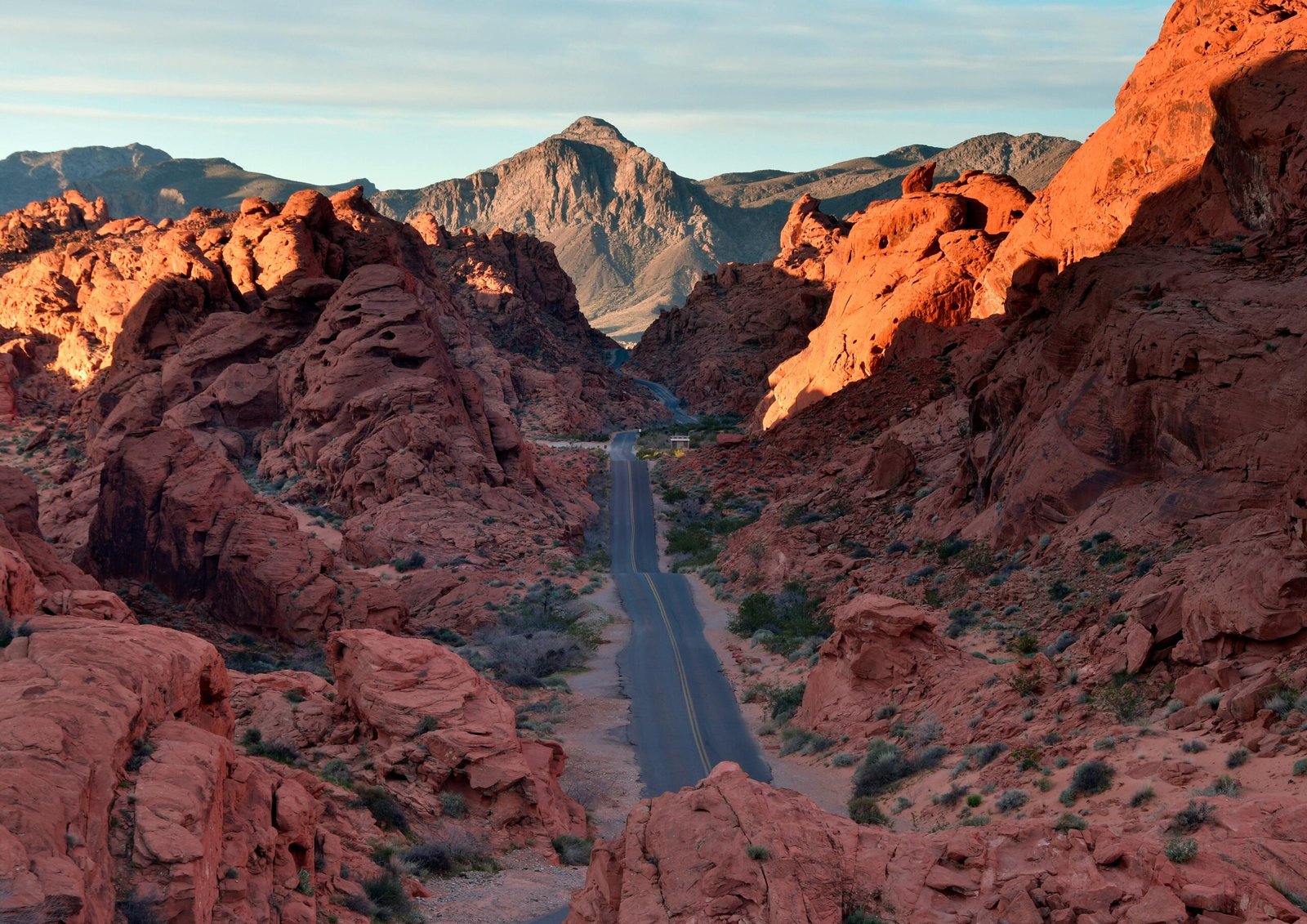 Vibrant sunset over the vast Mojave Desert landscape near Las Vegas, with the sun's golden light illuminating the iconic red sandstone formations of Valley of Fire State Park.