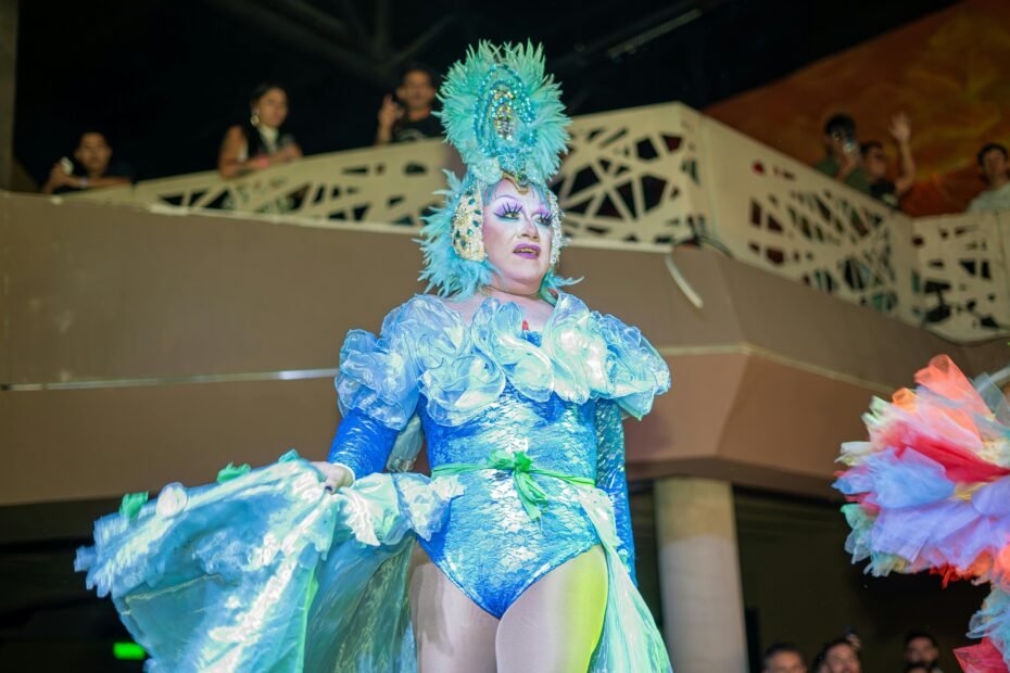 A drag queen performs in a fabulous, glittering costume on a brightly lit stage, capturing the fun of the Priscilla Queen of the Desert musical 2025 UK tour.