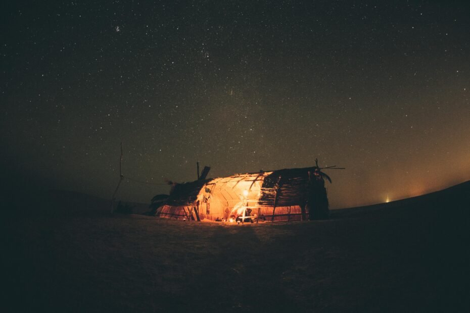 Enchanting luxury desert camp in the Moroccan Sahara at night, showcasing comfortable tents under a breathtaking star-filled sky and golden dunes.