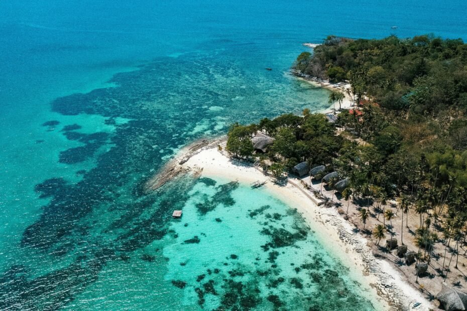 A stunning tropical paradise beach with white sand and crystal-clear turquoise water, representing the search for the best island to visit in 2025.