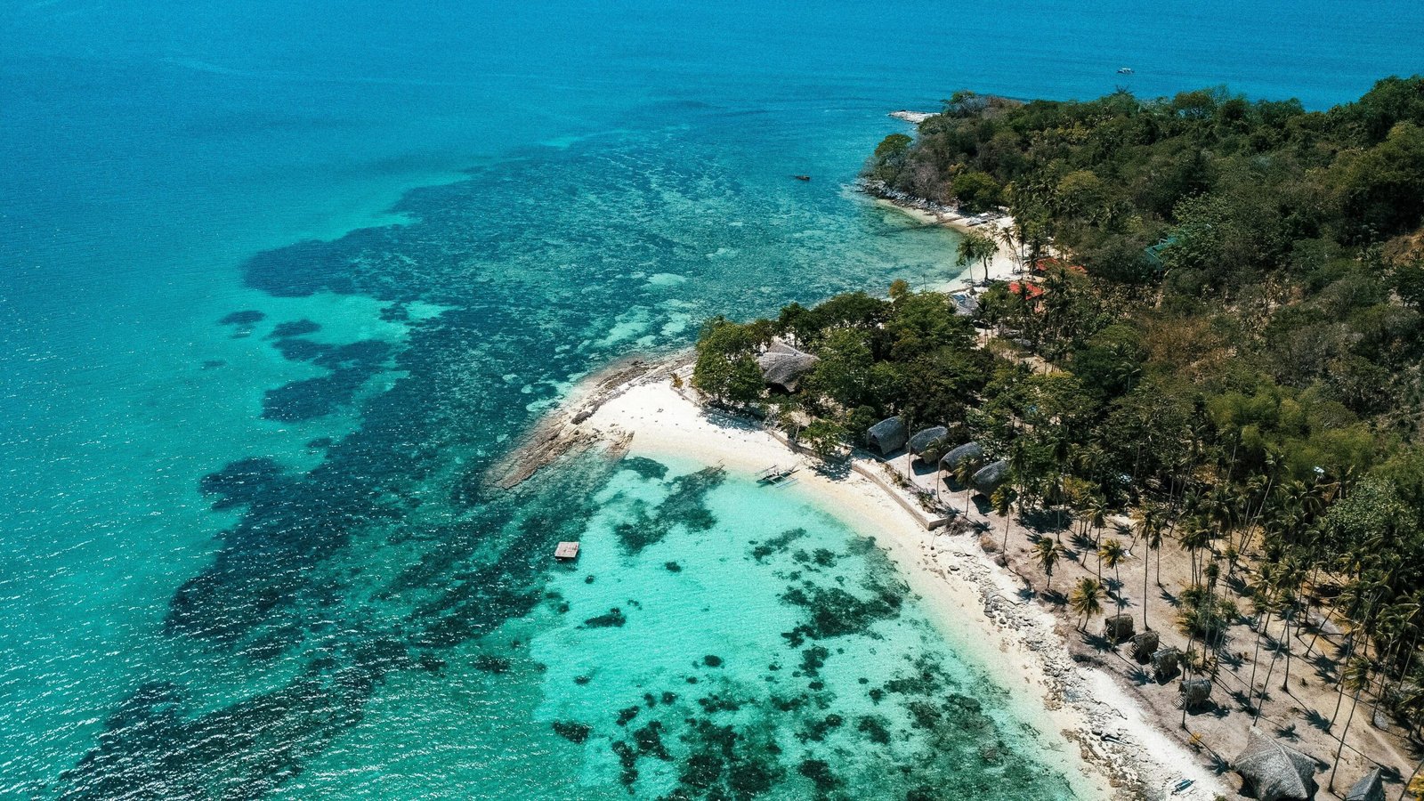 A stunning tropical paradise beach with white sand and crystal-clear turquoise water, representing the search for the best island to visit in 2025.