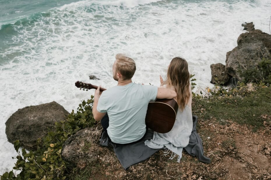 Musician playing a portable travel acoustic guitar in a beautiful outdoor setting, emphasizing the convenience and joy of music on the go.