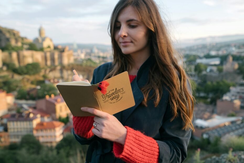 A solo female traveler writing in her journal, finding inspiration in a beautiful landscape, representing the authentic stories found on the best female travel blogs of 2024.