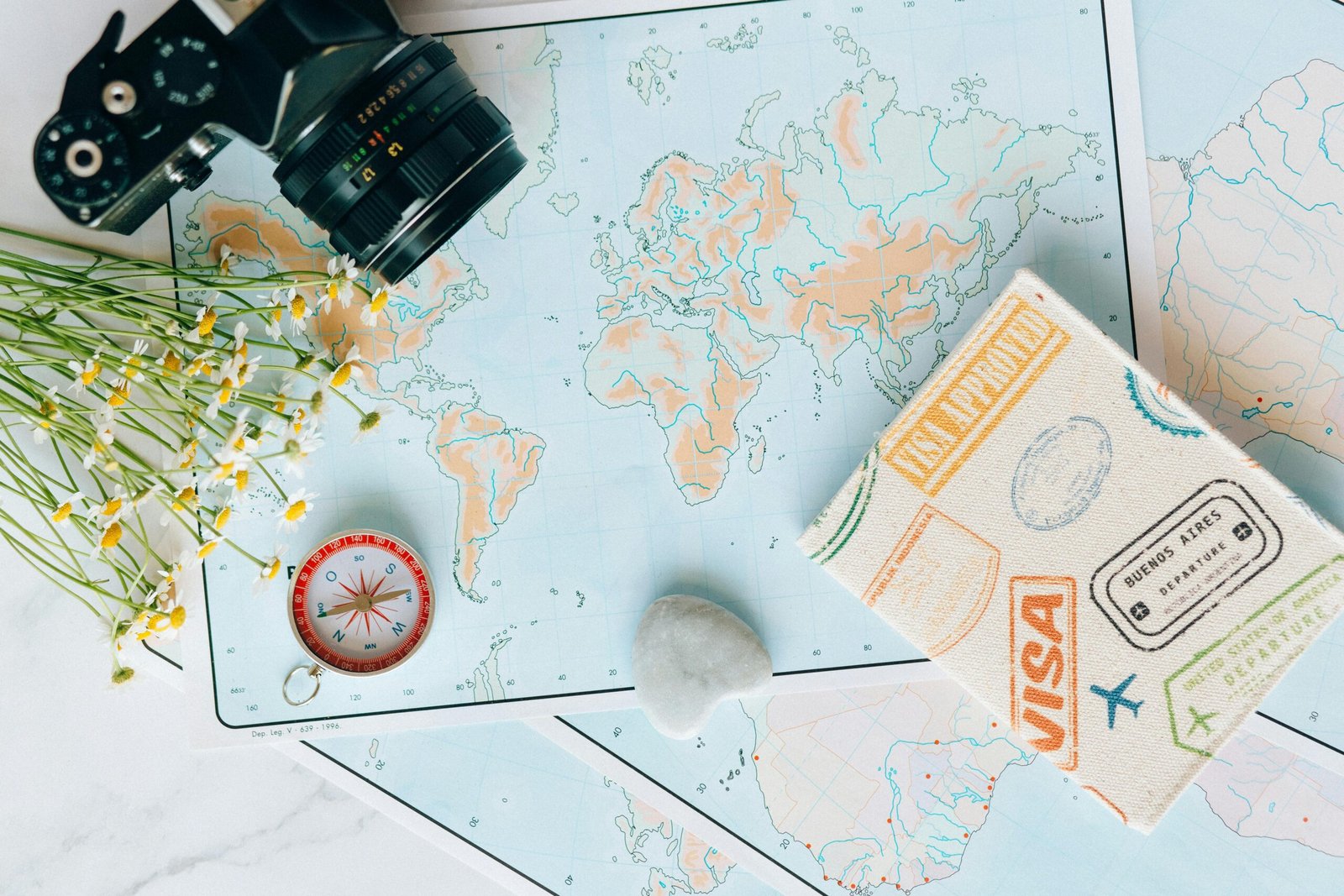 A traveler plans their next trip using an open Lonely Planet book and a map spread out on a wooden table, ready for adventure.