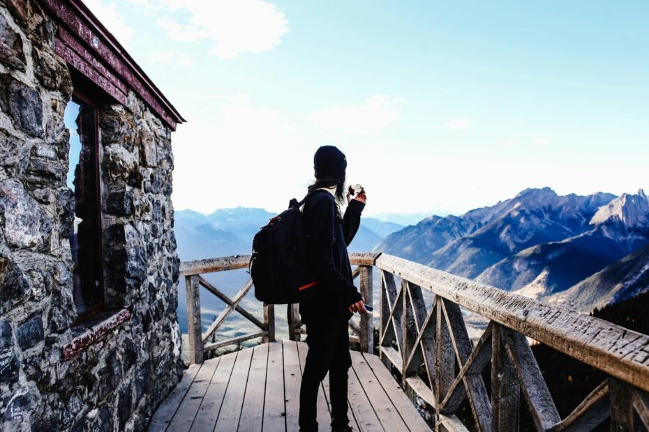 A traveler with a backpack stands on a mountain peak, looking out at a stunning valley at sunrise, illustrating an adventurous trip to one of the cheapest countries to travel to in 2025.