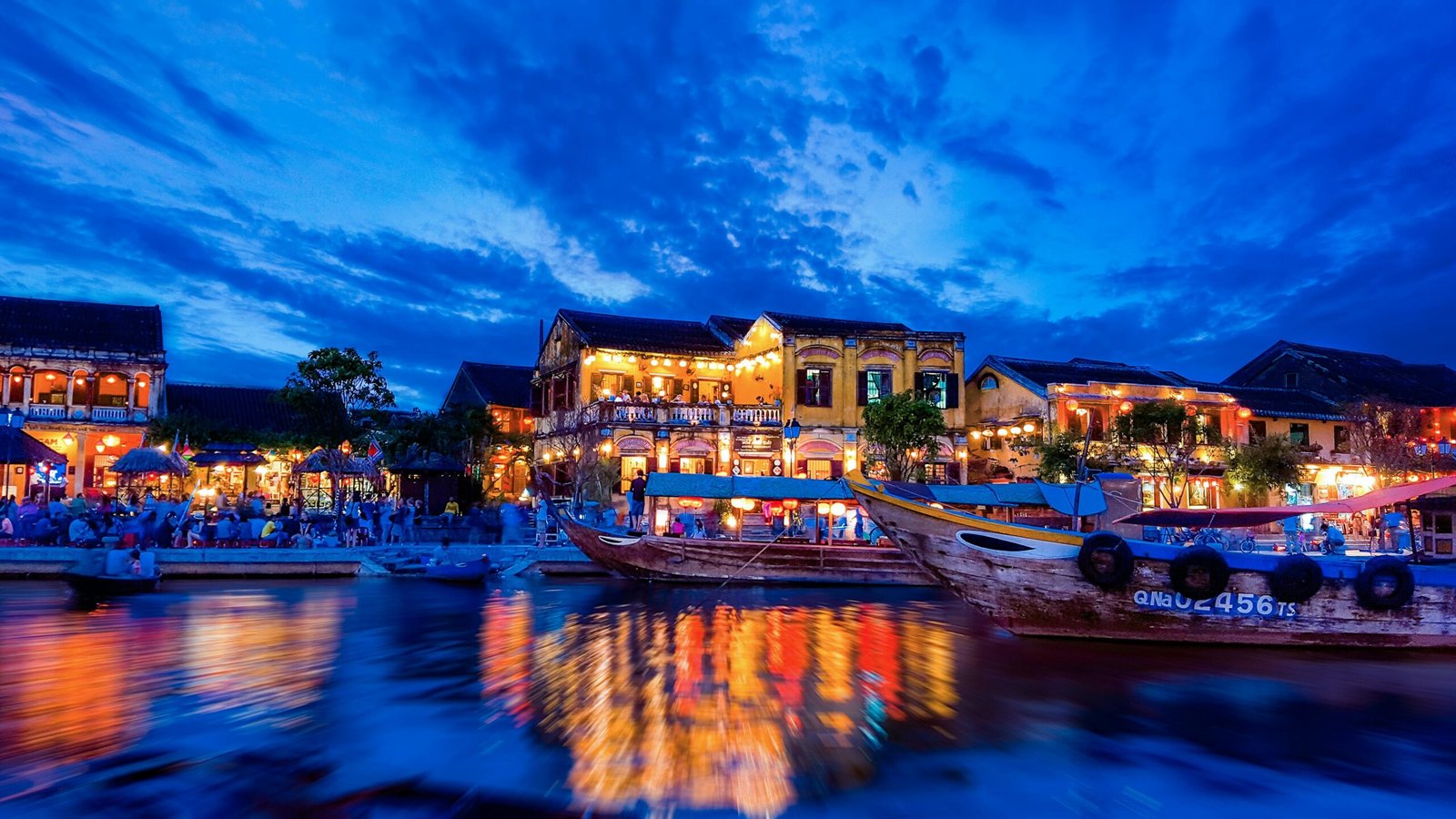 Colorful lanterns glowing at night over the river in the ancient town of Hoi An, one of the best cities to visit in Vietnam.