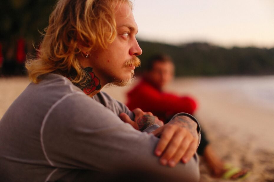 Person with a travel tattoo on their arm, such as a compass or map, looking thoughtfully at a scenic mountain landscape, symbolizing wanderlust, personal journeys, and cherished travel memories.