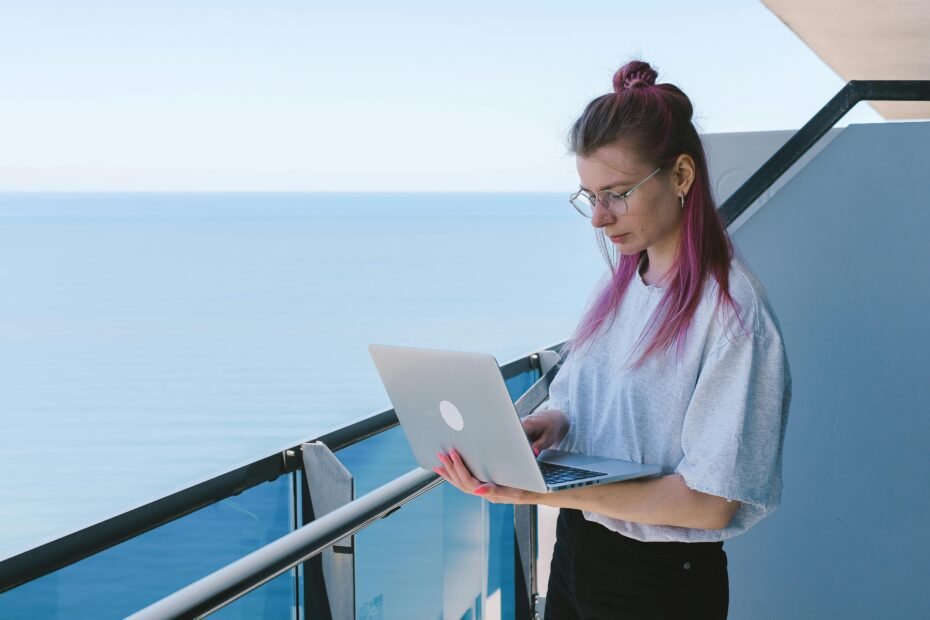 A person happily working on a laptop with a beautiful travel backdrop, symbolizing the passive income and freedom offered by travel affiliate programs for content creators.