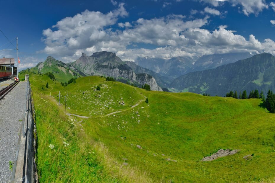 Panoramic view of the majestic Jungfrau region in the Swiss Alps, with a scenic mountain train or cable car, illustrating the extensive travel options covered by the Jungfrau Travel Pass for easy exploration.