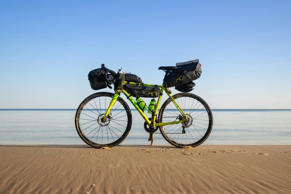 A cyclist pulling a black, wheeled bike travel bag through a bustling airport terminal, ready for an international cycling adventure.