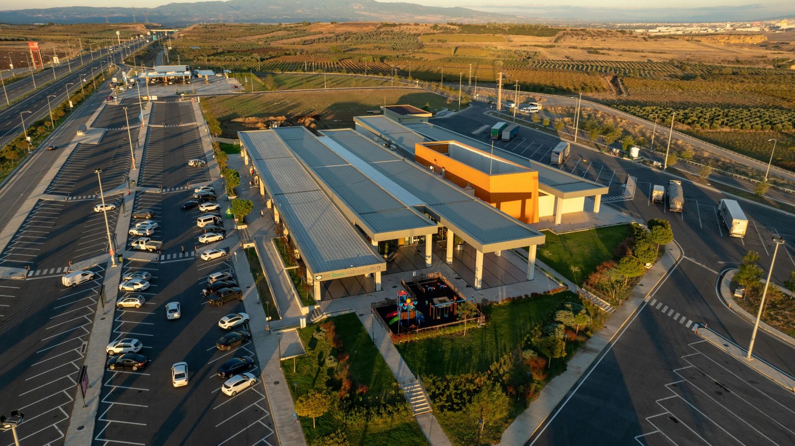 Exterior view of the TA Travel Center East Guasti Road Ontario CA at dusk, featuring semi-trucks at fueling stations and parked, highlighting its full range of services for drivers and travelers.