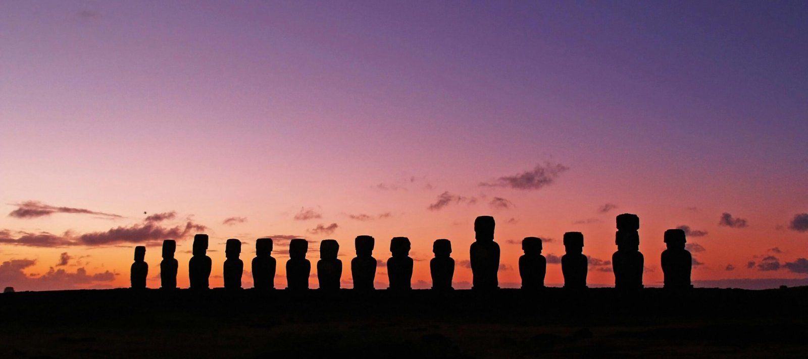 Iconic moai stone statues standing on the remote, ancient landscape of Easter Island (Rapa Nui), inviting travelers to explore its unique history.