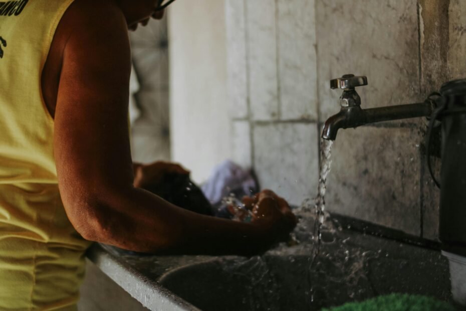 Close-up of a traveler's hands handwashing a t-shirt in a hotel sink with travel laundry soap, emphasizing lightweight packing and fresh clothes on the go.