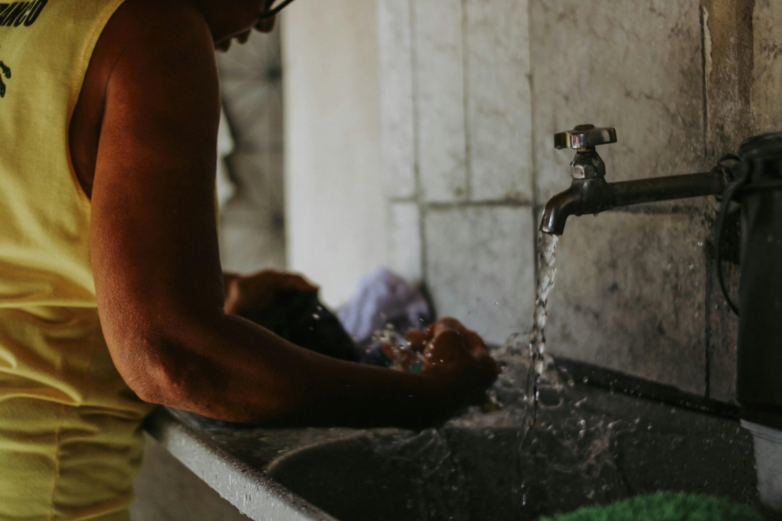 Close-up of a traveler's hands handwashing a t-shirt in a hotel sink with travel laundry soap, emphasizing lightweight packing and fresh clothes on the go.