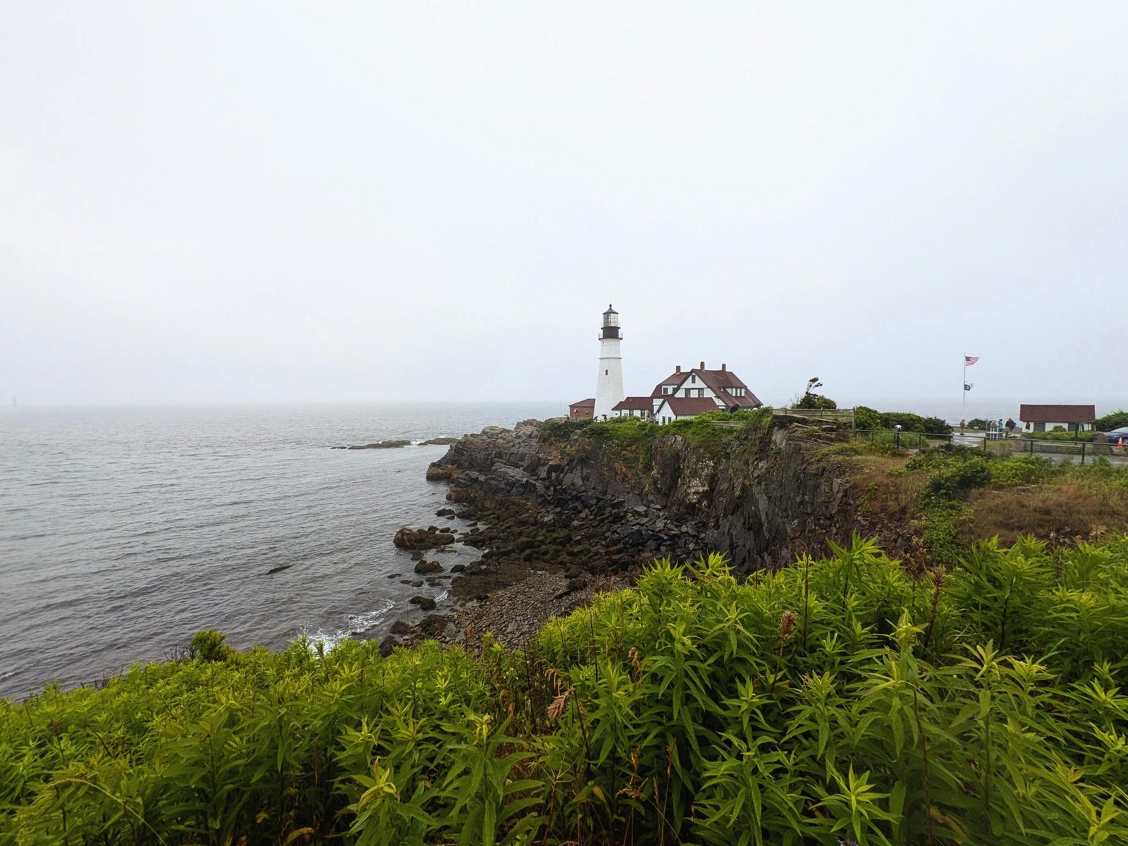 Scenic coastal view highlighting a classic Maine lighthouse and charming town, representing the best Maine travel destinations for nature, food, and coastal charm.