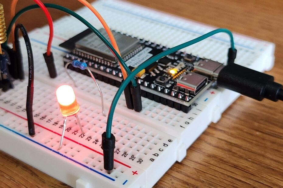 Close-up of an electronics breadboard circuit with an LED, resistor, and jumper wires, demonstrating current flow and connections for beginner prototyping.