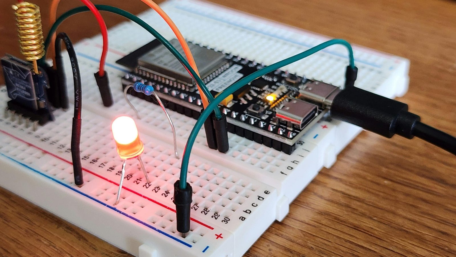 Close-up of an electronics breadboard circuit with an LED, resistor, and jumper wires, demonstrating current flow and connections for beginner prototyping.