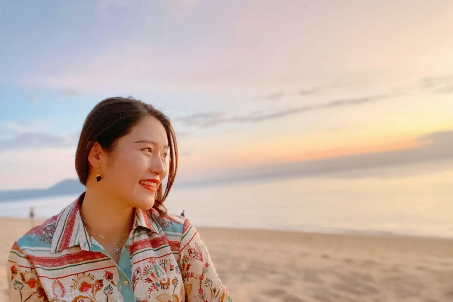 Happy young woman enjoying a beautiful tropical beach in Thailand with crystal clear water and palm trees, symbolizing peace of mind and safe travel with comprehensive travel insurance.