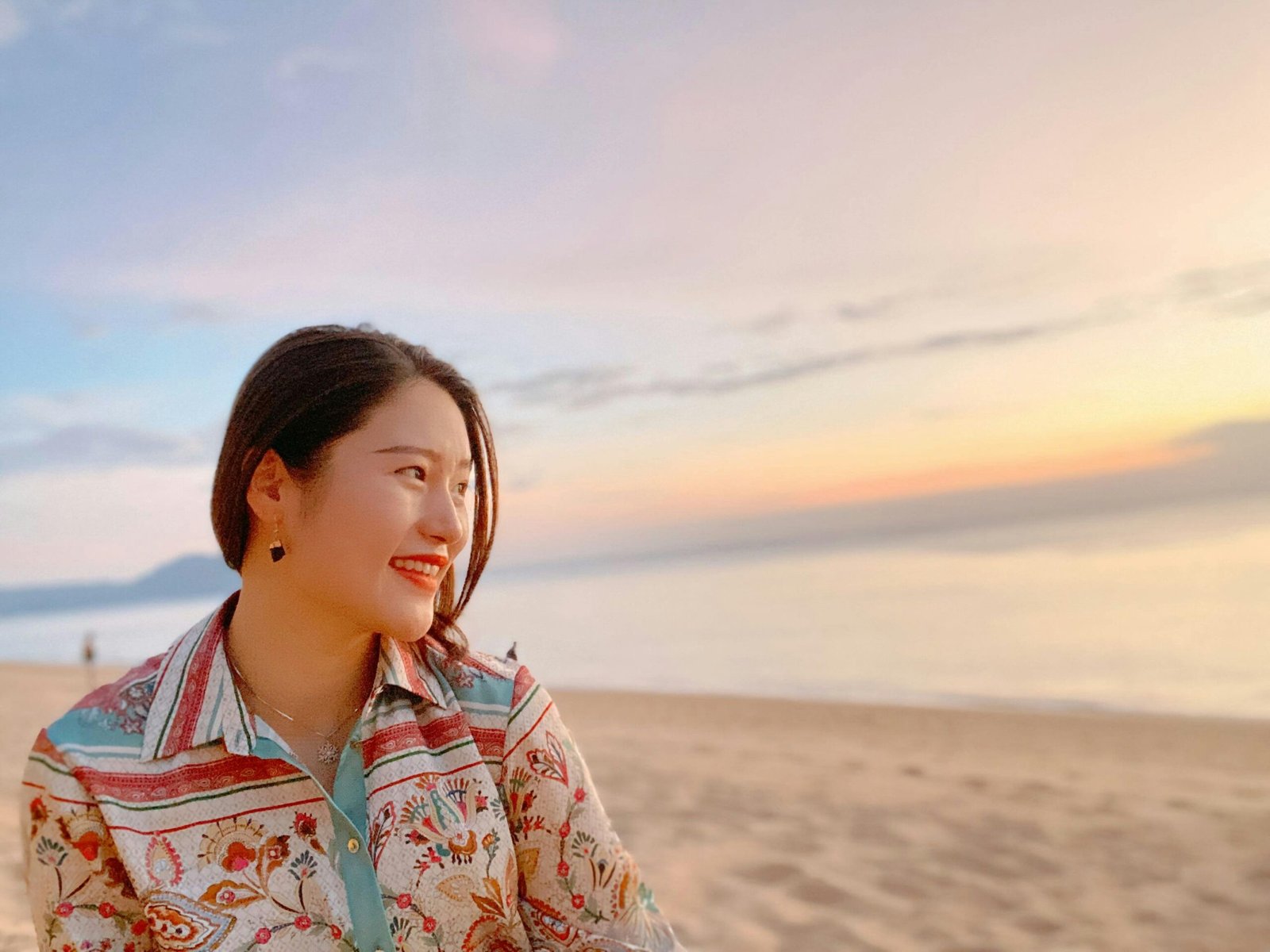 Happy young woman enjoying a beautiful tropical beach in Thailand with crystal clear water and palm trees, symbolizing peace of mind and safe travel with comprehensive travel insurance.