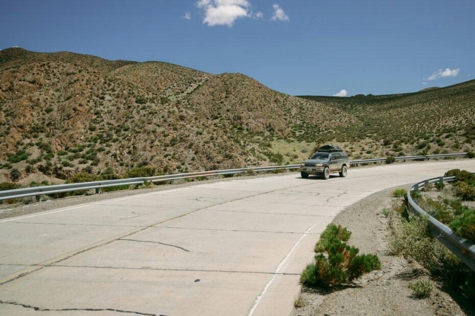 Car driving downhill safely on a winding mountain road, illustrating effective engine braking and controlled descent techniques to prevent brake fade.