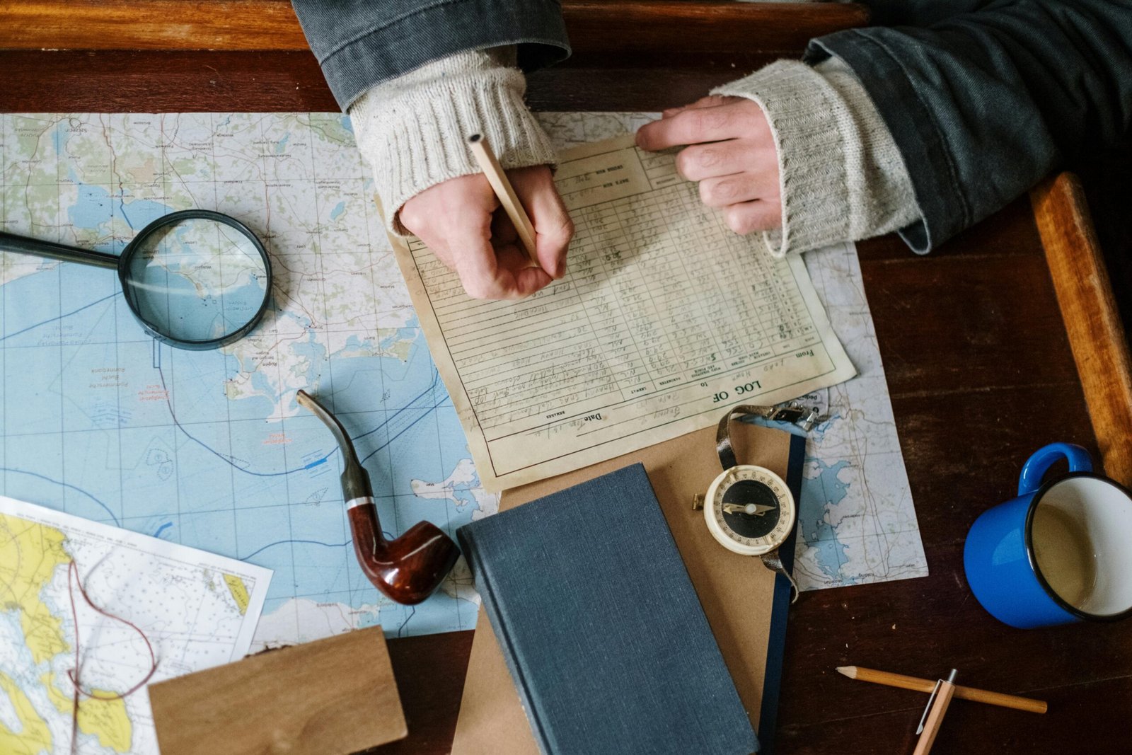Hand writing in a classic leather traveler's journal, open on a wooden surface with a pen and map, symbolizing authentic travel memories, adventure planning, and personal reflection.