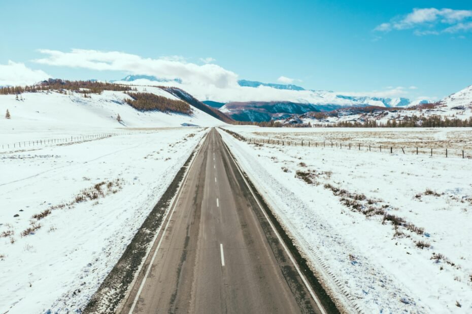 Winter driving on a snowy Wyoming highway with distant mountains, illustrating safe travel and checking WYDOT road conditions.