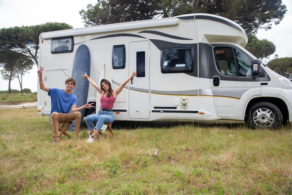 Grand Design Imagine travel trailer in a beautiful natural setting with a couple, emphasizing luxury camping, lightweight design, and the freedom of the open road.