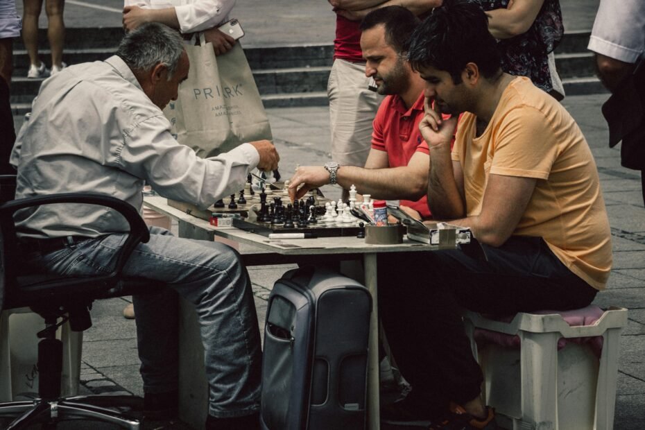 Close-up of hands playing chess on a portable magnetic travel chess set, set against a blurred background of a train window or scenic outdoor adventure, highlighting convenient intellectual entertainment on the go.