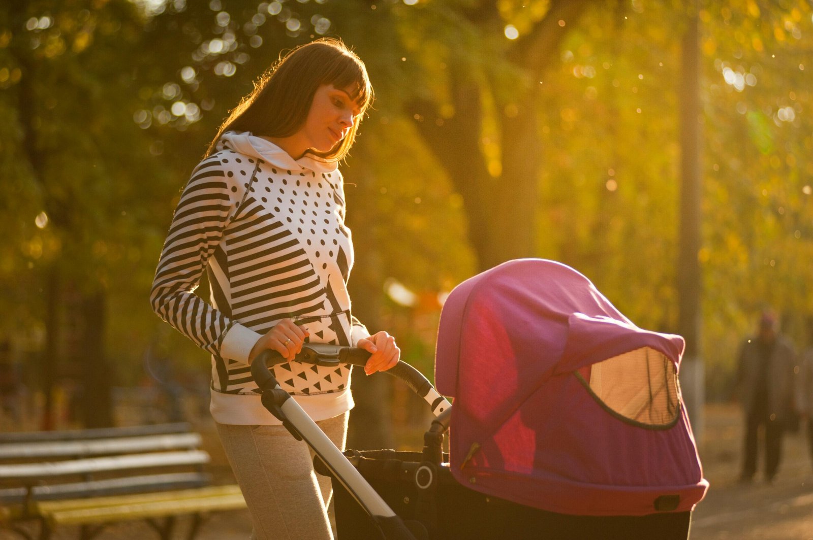 A parent comfortably pushing a baby in a versatile travel system stroller with an infant car seat attached, illustrating the convenience and safety of Baby Trend's all-in-one solution for newborns and active families.