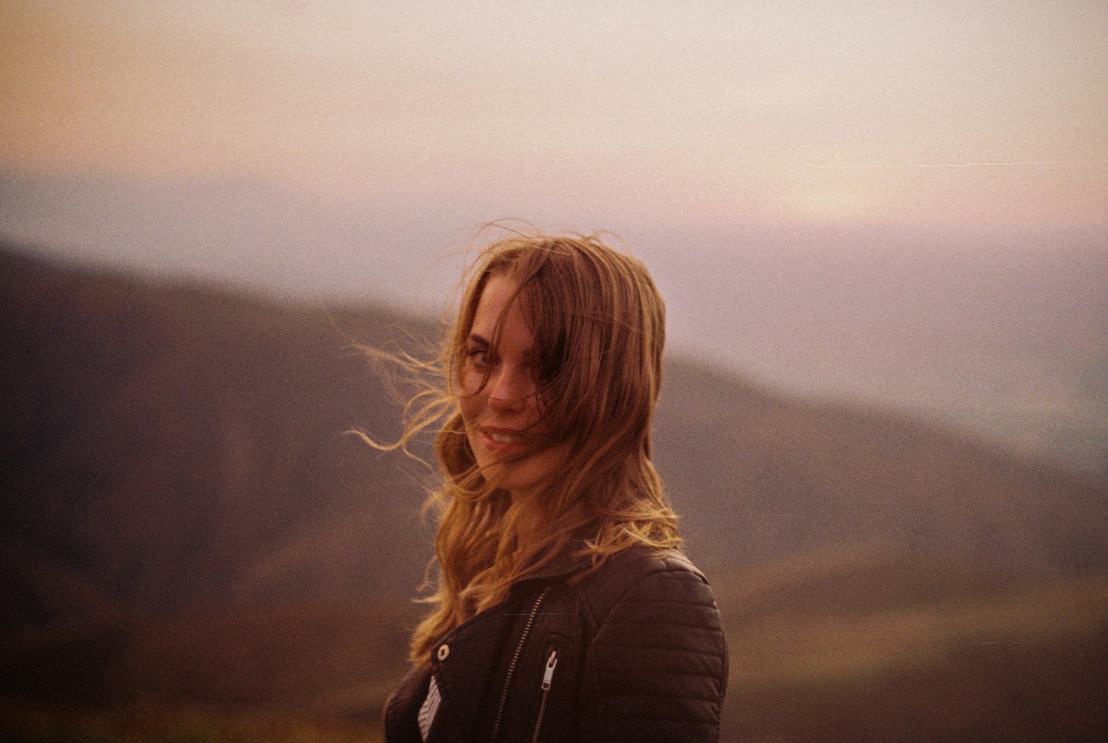 Woman traveler refreshing hair with Batiste dry shampoo travel size for instant volume and freshness on any adventure.