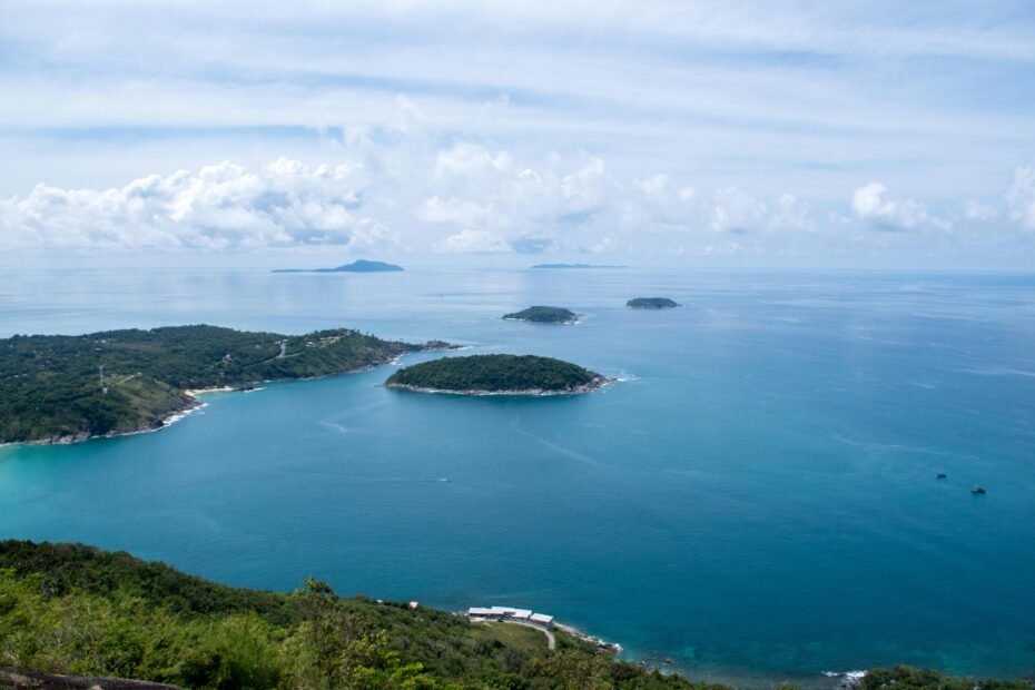 Phuket best time to travel: Idyllic tropical beach scene with clear turquoise water, white sand, lush palms, and blue sky, representing the perfect dry season vacation in Thailand.