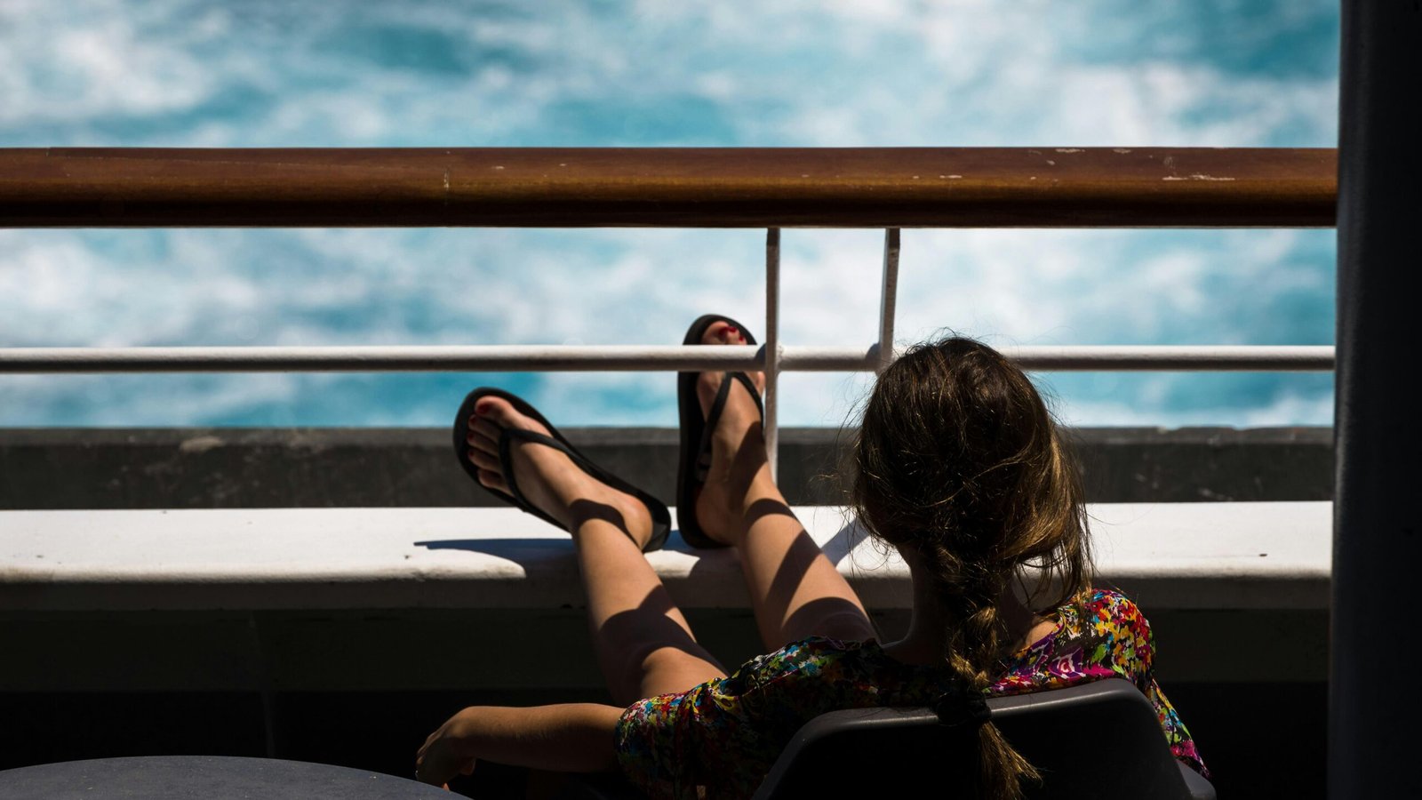 Happy person on a cruise ship deck looking at the calm ocean horizon, symbolizing effective seasickness prevention for an enjoyable and smooth cruise vacation.