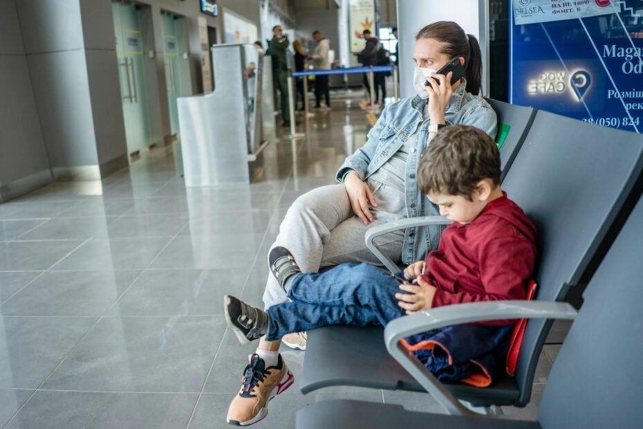 Parent easily carrying a compact foldable travel car seat for a 2-year-old through an airport terminal, highlighting portability and convenience for family air travel.