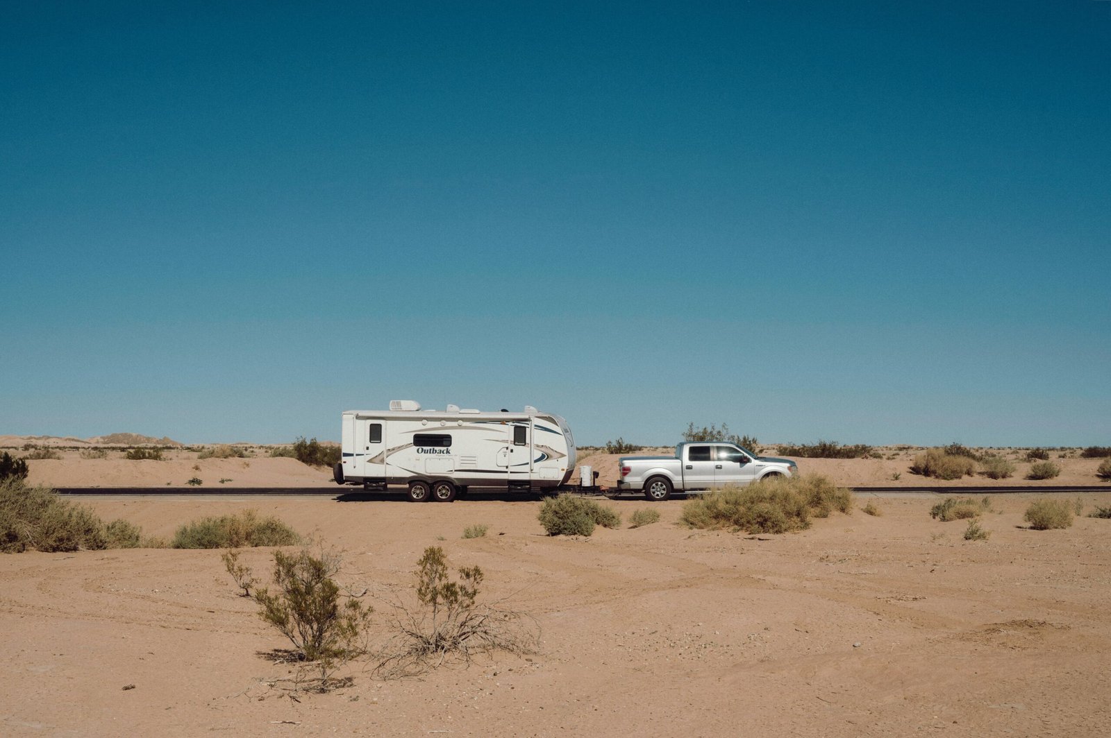 Rugged off-road travel trailer with high ground clearance parked in a remote mountain wilderness, ready for adventure and off-grid exploration.