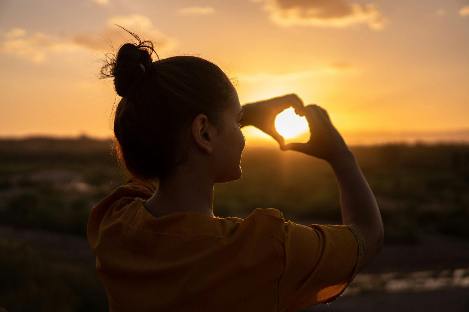 Close-up of hands clasped in prayer, bathed in warm, ethereal light, symbolizing spiritual protection and safe travels for a loved one's journey.