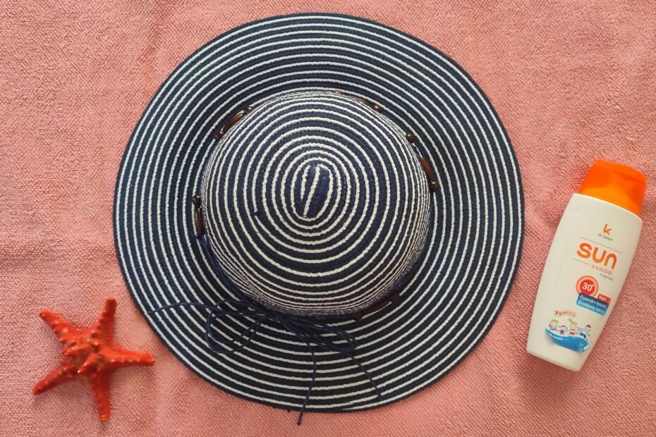 Close-up of a travel size SPF sunscreen bottle or stick in a hand against a sunny beach background, symbolizing easy sun protection for vacation carry-on.