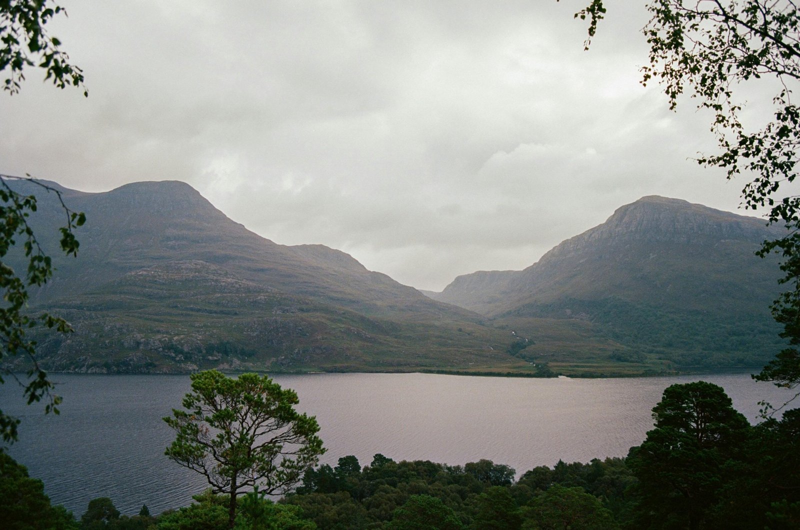 Majestic Scottish Highlands landscape with a tranquil loch and distant castle, illustrating unforgettable Scotland travel packages for your next adventure.