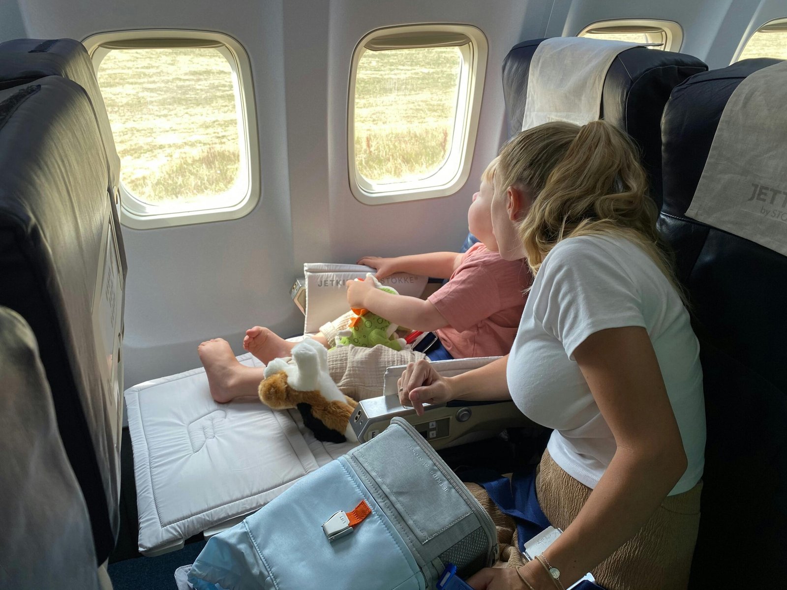 Young child safely secured in an FAA approved travel car seat on an airplane, providing comfort and safety for family air travel.