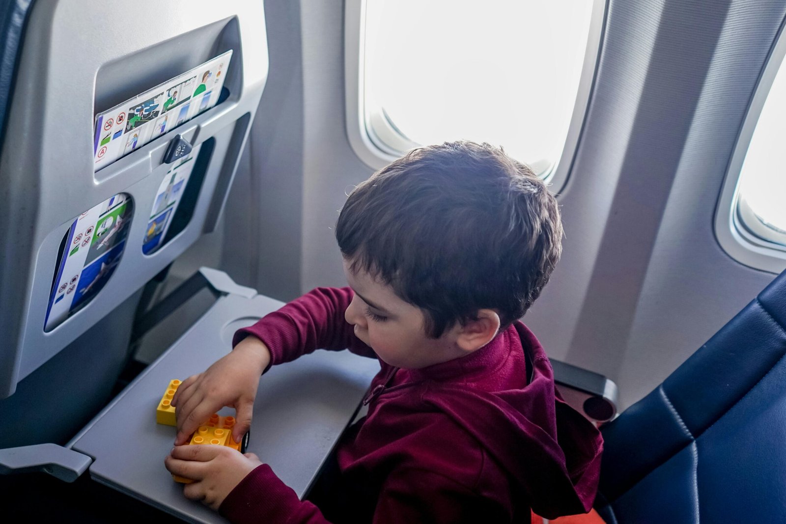 Happy child playing quietly with a travel toy on an airplane, keeping kids entertained and making family trips peaceful and stress-free.