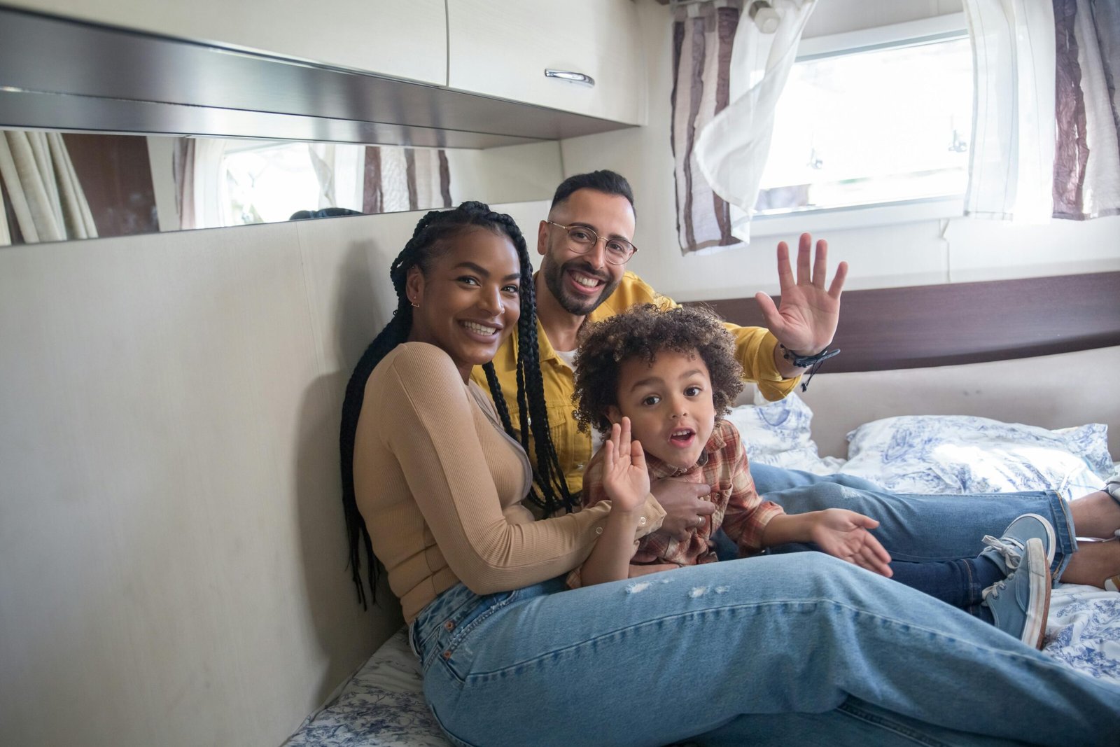 Happy family relaxing in a spacious two bedroom travel trailer interior, showing children and parents enjoying privacy and comfort during a family road trip.